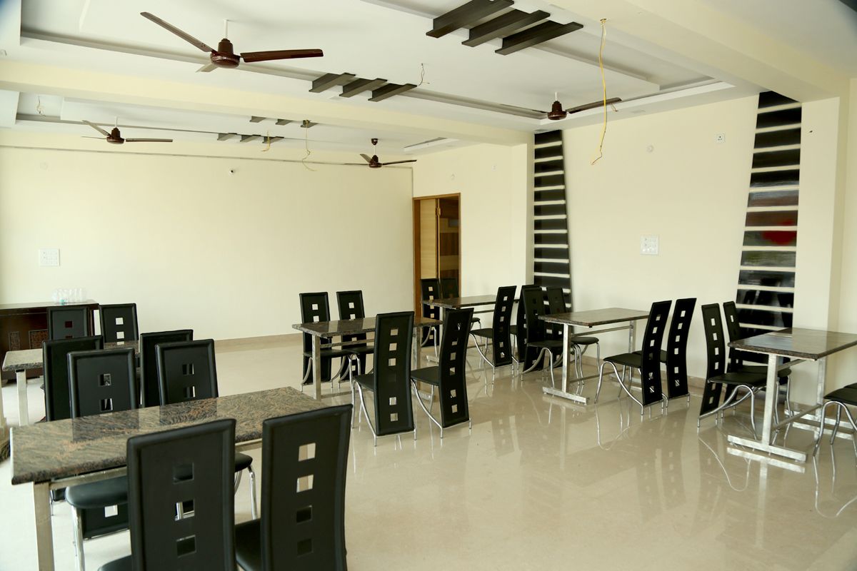 A spacious dining area with multiple tables and chairs, ceiling fans, and a modern design.