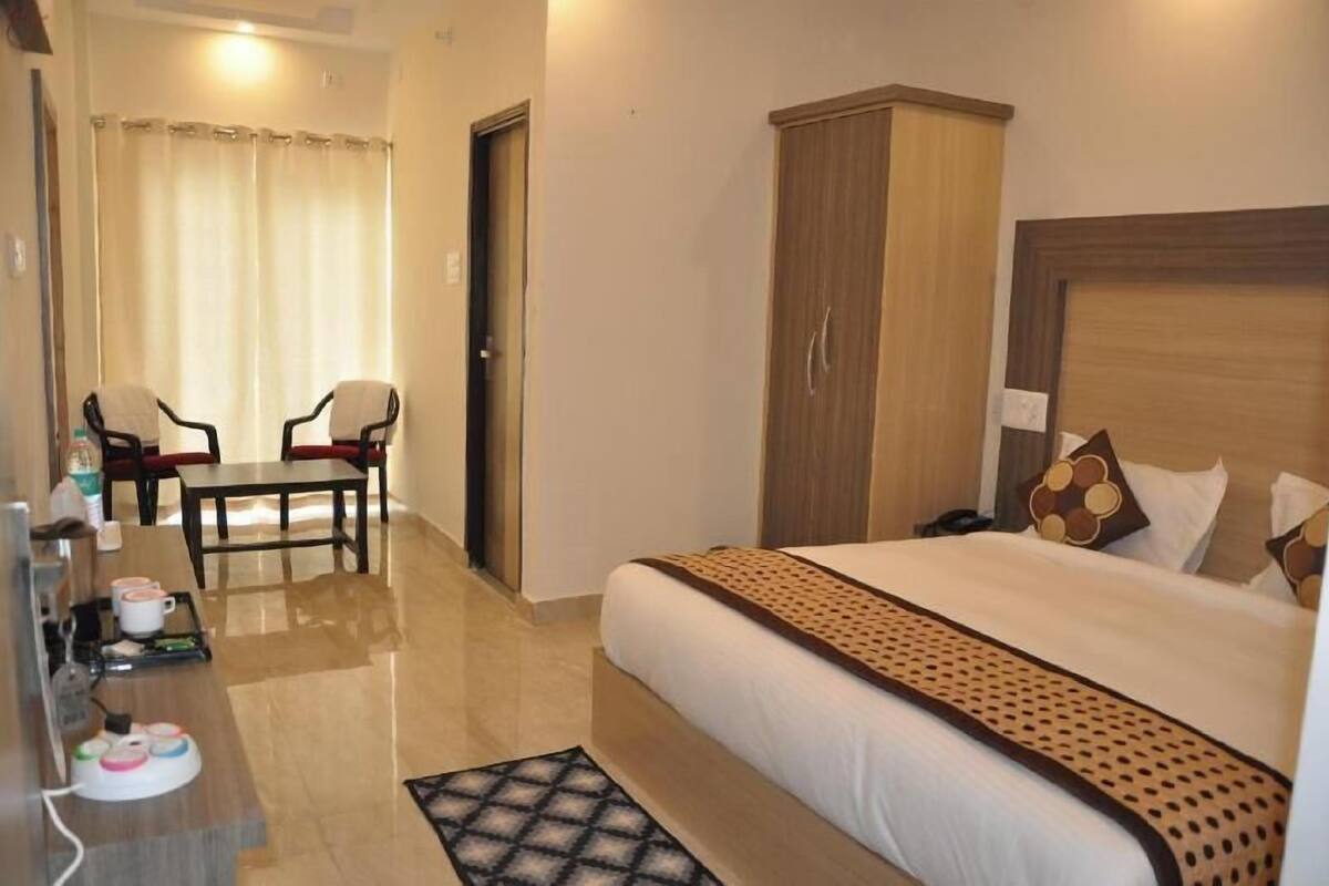 A hotel room with a bed, a desk with a chair, a wardrobe, and a bathroom with a shower curtain.