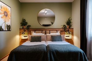 A double bed with a wooden headboard, two bedside tables with lamps, and a large mirror above the bed.
