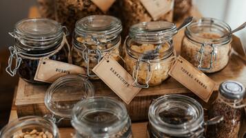 A variety of glass jars with labels on a wooden surface, likely containing different food items or condiments.