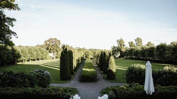 A garden pathway leading to a seating area with white chairs and a white umbrella.