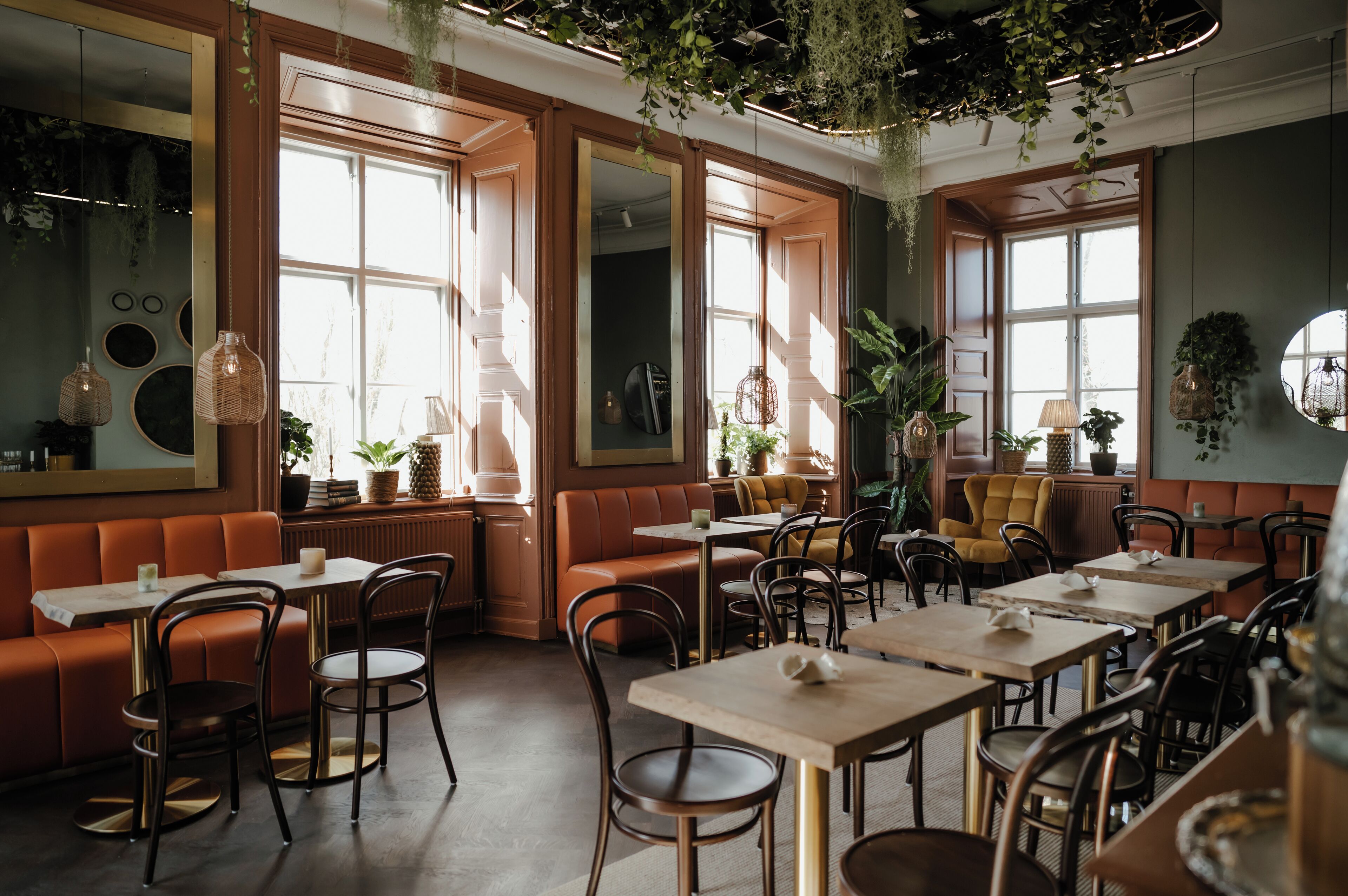Un restaurante con cabinas, mesas y plantas colgantes.