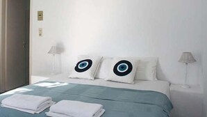 Una habitación de hotel con una cama, dos almohadas de diseño circular, una mesita de noche con una lámpara y una puerta.