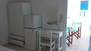Una cocina funcional con refrigerador, una mesita y una silla.