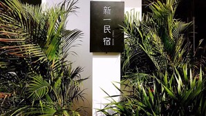 A sign with Chinese characters, surrounded by lush green plants. - xinyi (Huairou)