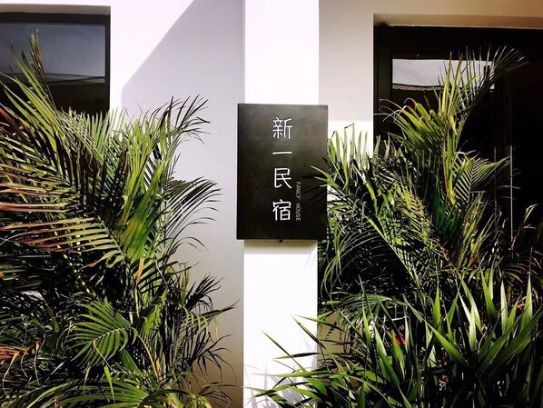 Une enseigne ornée de caractères chinois, entourée d’une végétation luxuriante.