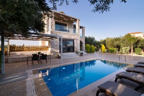 Een buitenzwembad, ligstoelen bij het zwembad