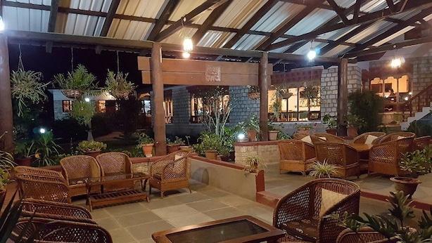 An outdoor seating area with wicker furniture and potted plants. - Kichu Resort (Wangdue Phodrang)