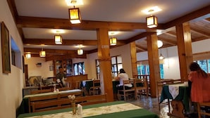 A restaurant with wooden beams, green tablecloths, and hanging lanterns. - Kichu Resort (Wangdue Phodrang)