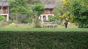 A traditional wooden building with a tiled roof, surrounded by lush greenery and a well-maintained garden. - Kichu Resort (Wangdue Phodrang)
