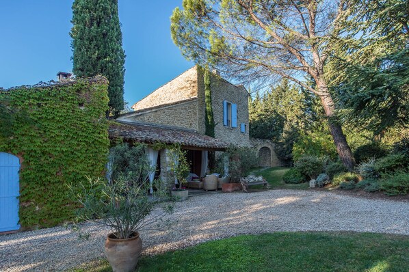 Surrounded by lush greenery, this traditional house offers a tranquil setting with a covered porch and outdoor seating.