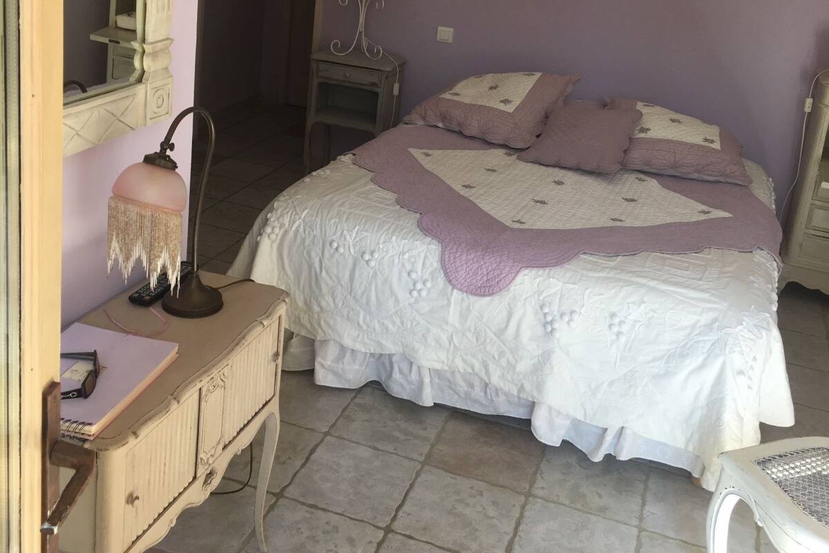 A bedroom with a bed, dresser, mirror, lamp, and a chair.