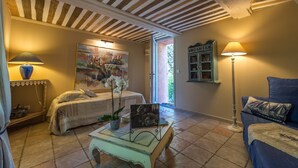 Une pièce confortable avec un lit, une table surmontée d’une lampe, un tableau et une vue sur l’extérieur.