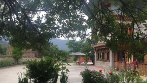 A traditional building with a stone facade, surrounded by lush greenery and flowering plants. - Ngayabling Resort (Paro)