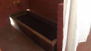 A room with a brick wall, a window with white curtains, and a door with a brass handle. - Ngayabling Resort (Paro)