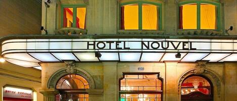 Un edificio histórico con un cartel luminoso que dice 'HOTEL NOUVEL'.