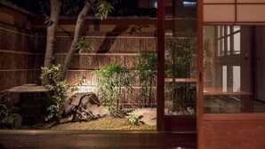 A traditional Japanese-style garden with bamboo, a stone lantern, and a wooden fence. - HANARé Genmachi (Kyoto)