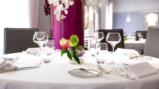 A dining table set with white tablecloth, silverware, and clear glasses, surrounded by chairs. - Logis Auberge du Cheval Blanc (Westhalten)