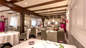 A restaurant with white tablecloths, wooden beams, and floral centerpieces. - Logis Auberge du Cheval Blanc (Westhalten)