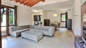 A spacious living area with a large sectional sofa, a dining table, and a kitchen in the background. - Exclusive Villa with Sea View – Rio nell’Elba: Villetta Natura Casa A (Rio nell'Elba)