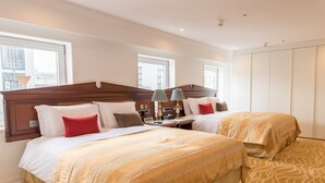 A hotel room with two beds, a wooden headboard, a nightstand with lamps, and a wardrobe. - IP CITY HOTEL Osaka (Osaka)