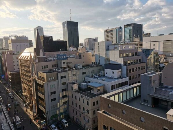 Un paisaje urbano con edificios modernos, incluyendo un rascacielos destacado y un edificio con un cartel que dice