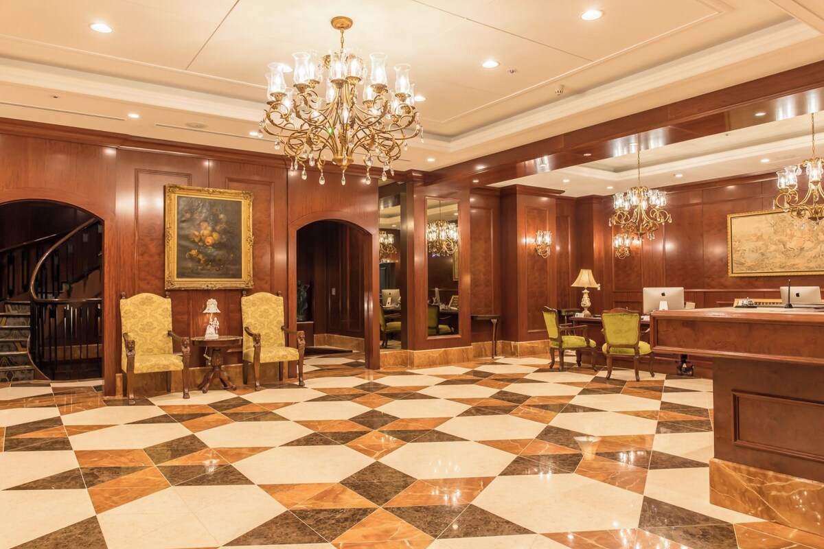 A lobby with a checkered floor, a reception desk, and a staircase.