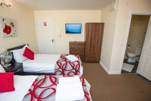 A hotel room with two beds, a wardrobe, a television, and a bathroom. - Bradford City Apartments Flat 74 (Bradford)