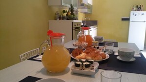 Een ontbijttafel met een karaf sinaasappelsap, gebak, honing en toevoegingen.