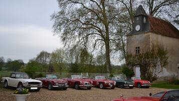 Eine Reihe klassischer Autos vor einem Gebäude mit einem Glockenturm.
