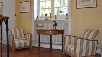 Une pièce avec deux fauteuils à rayures, une table en bois et un radiateur.