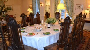 Un comedor formal con una mesa redonda dispuesta para una comida, rodeada de sillas de madera.