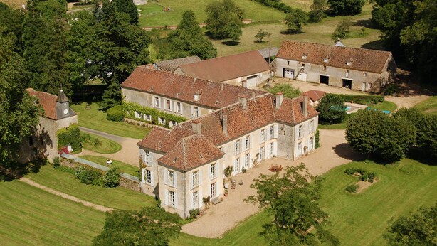 Una extensa propiedad con varias edificaciones, un césped impecable y un campo de golf.