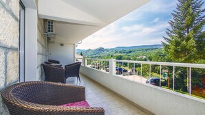 Een balkon met rieten meubilair, uitzicht op een groen landschap en een bord dat een parkeerplaats aangeeft.