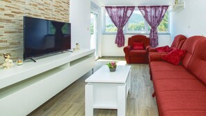 Een moderne woonkamer met een flatscreen televisie, een rode bank en een witte salontafel.