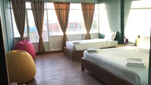 Een hotelkamer met twee bedden, een grote relaxfauteuil en uitzicht op het omliggende landschap.