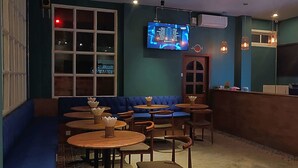 Een restaurant interieur met blauwe zitplaatsen, houten tafels, een televisiescherm en een Glacier ijsmachine.