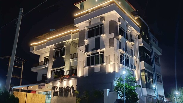Een hotel met meerdere verdiepingen, modern vormgegeven, met balkons en een goed verlichte gevel.