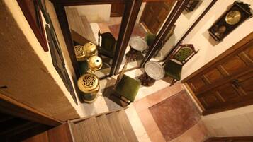 A room with a checkered floor, a green chair, a wooden cabinet, and a clock on the wall.