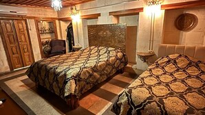 Une chambre avec deux lits, des poutres apparentes en bois au plafond et un lustre.