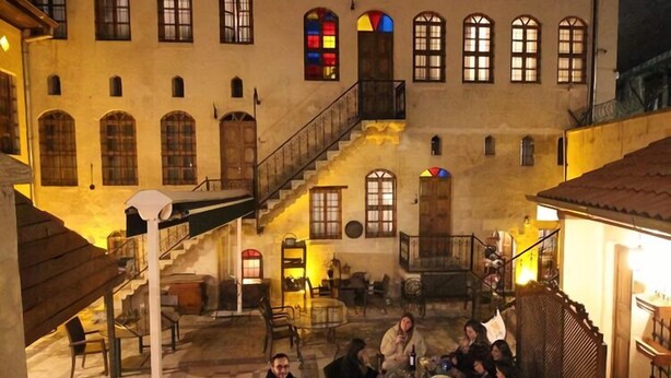 Une cour avec un foyer, des sièges extérieurs et un bâtiment doté de nombreuses fenêtres et d’un escalier.