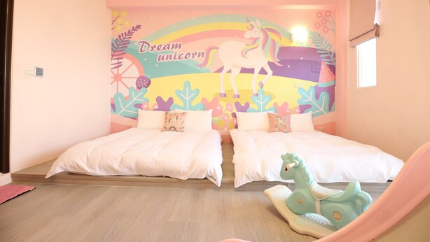 A bedroom with two beds, a mural of a unicorn, and a toy horse. - Dao Siang Hai B&B (Taitung)