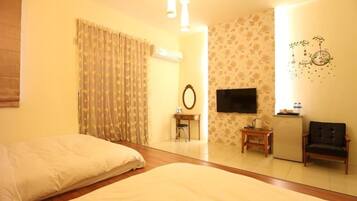 Habitación de hotel con cama, escritorio, silla, televisor y refrigerador.