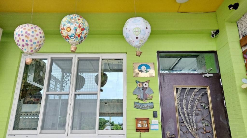 Un edificio con fachada verde, un ventanal grande y una puerta con detalles decorativos.