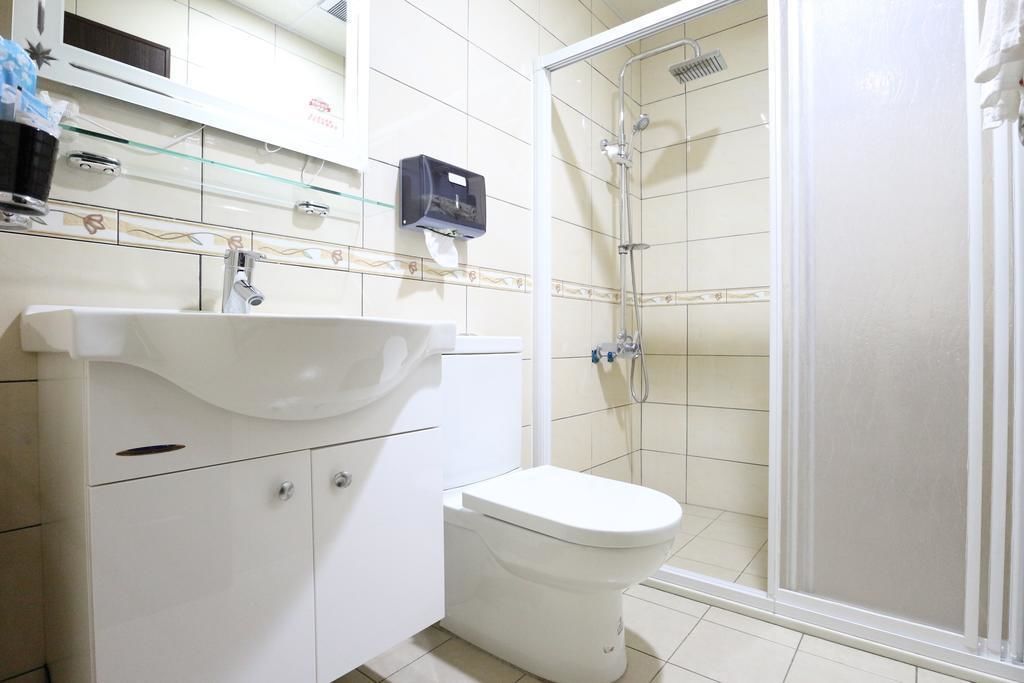 A bathroom with a white sink, toilet, and glass-enclosed shower.