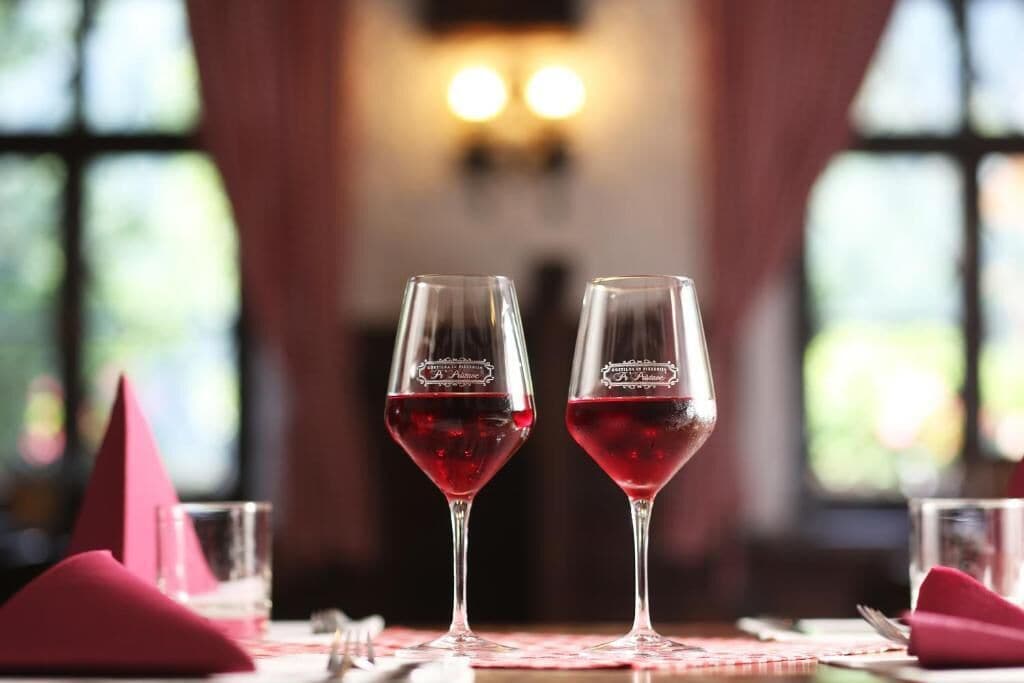 Two wine glasses on a table with a red napkin, a glass of red wine, and a red triangular napkin.