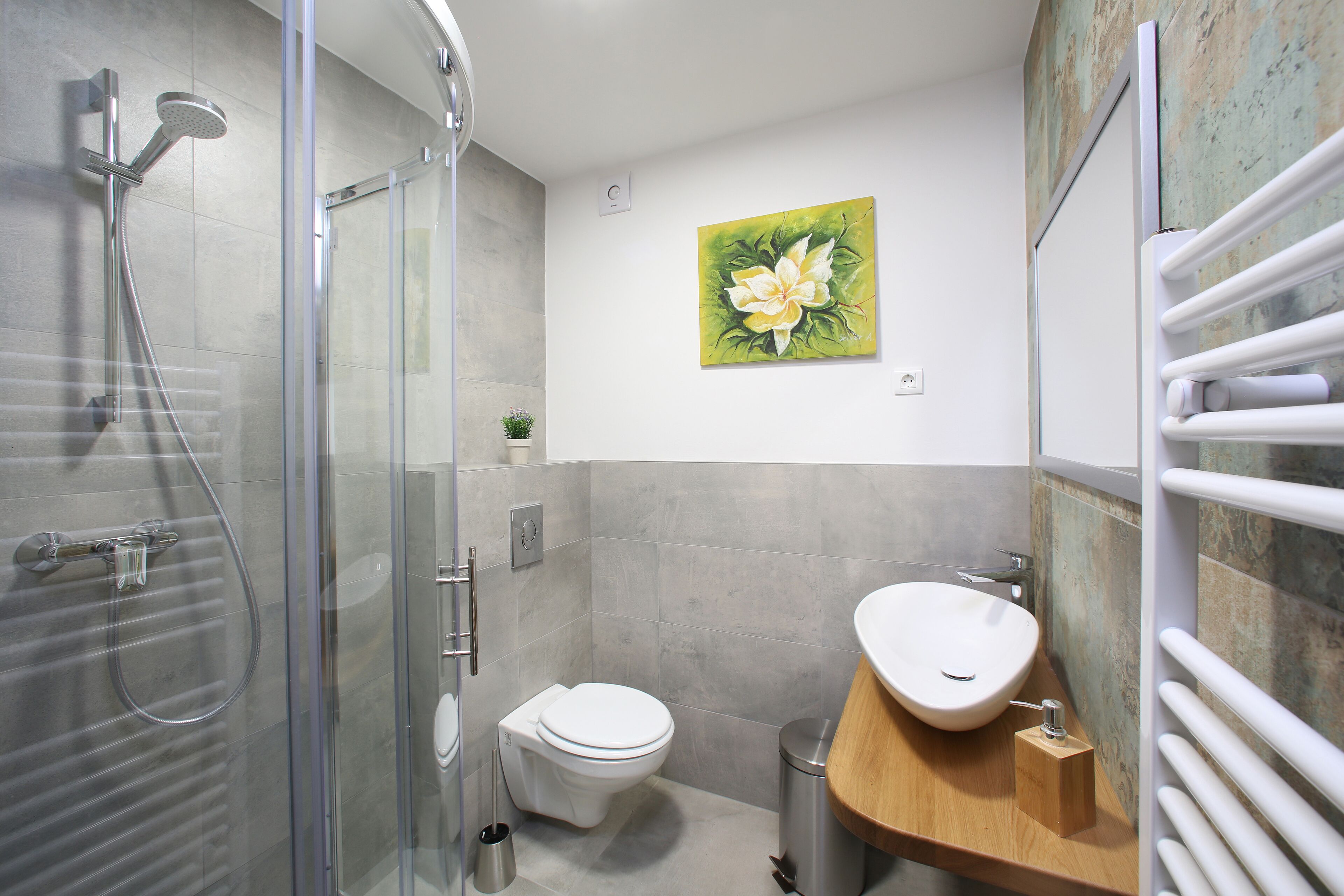 A modern bathroom with a glass-enclosed shower, a toilet, and a sink with a wooden countertop.