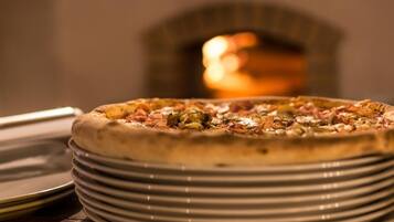 A pizza on a stack of plates with a blurred background of a fireplace.