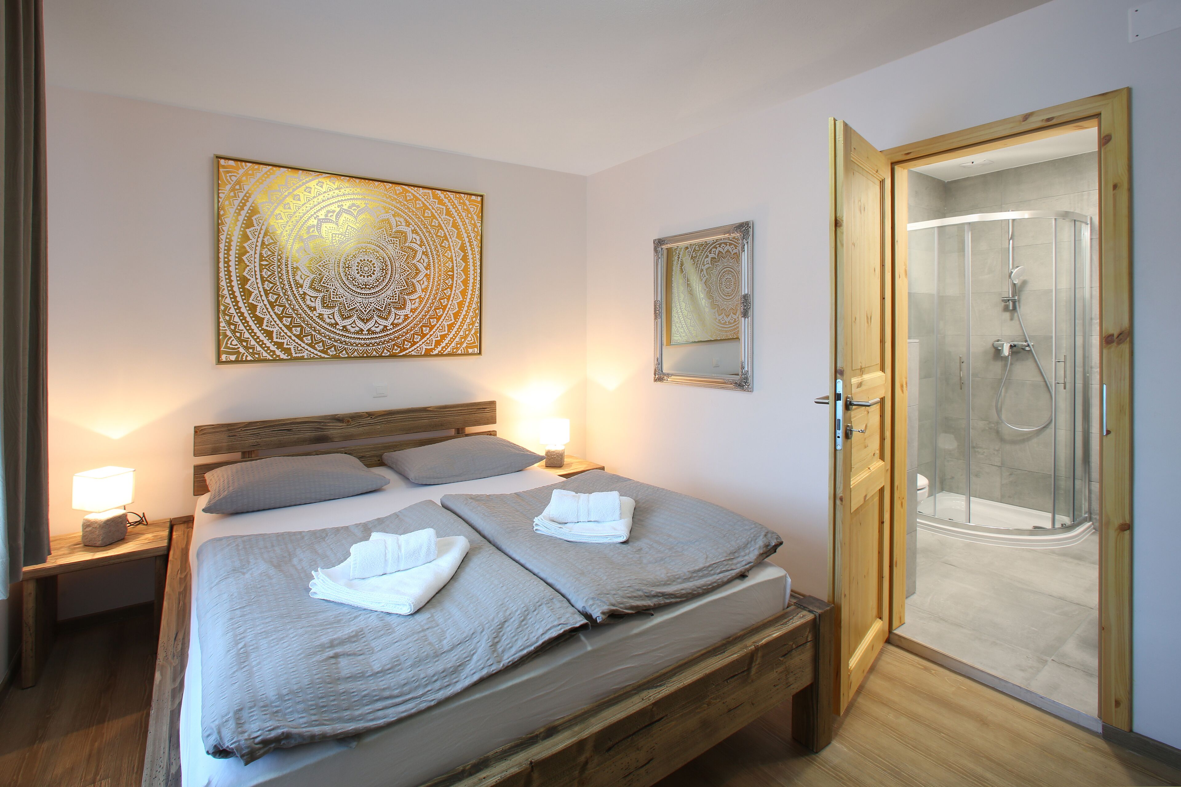 Quarto com cama, luminárias de cabeceira, chuveiro e obras de arte na parede.