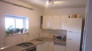 A compact kitchen with a gas stove, microwave, sink, and cabinets. - Apartments Biocic (Korcula)